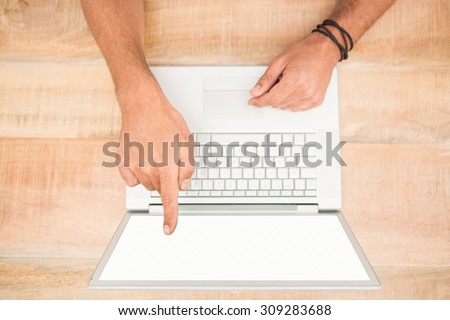 Hand pointing on blank laptop screen on wooden table