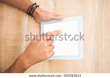Hand pointing blank screen tablet on wooden desk