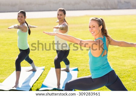 Portrait of yoga teacher and sporty women attending yoga class in parkland