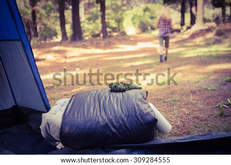 Sleeping bag in front of blonde camper walking away in the nature