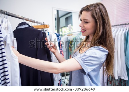 Woman taking a photo of price tag in fashion boutique