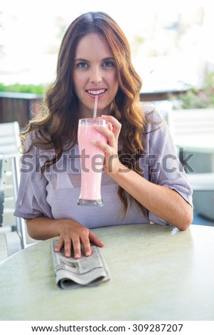 Pretty woman sipping smoothie outside at cafe on a sunny day