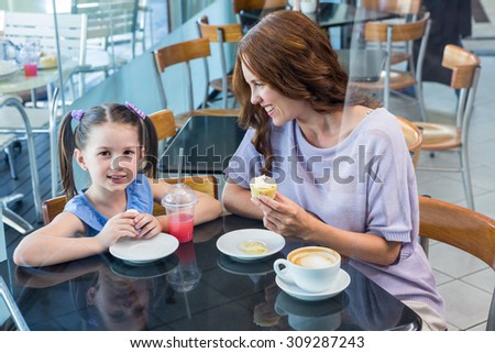 Mother and daughter enjoying cakes in coffee shop