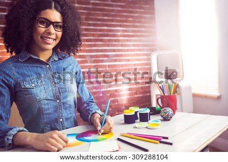 Portrait of casual female designer smiling and drawing at workplace