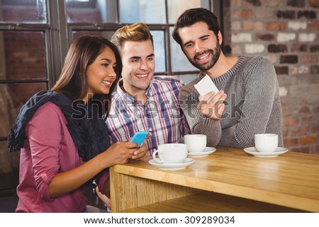 Group of friends looking at a smartphone in a cafe