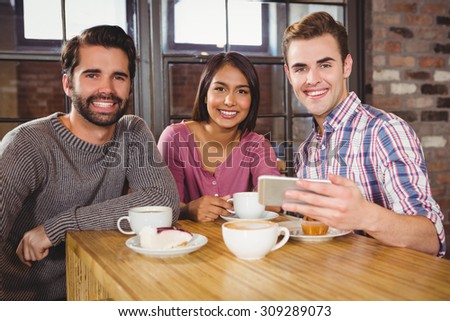 Group of friends looking at a smartphone in a cafe