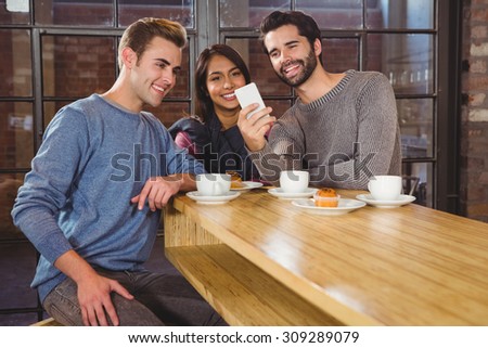 Group of friends looking at their smartphone in a cafe