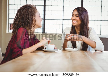 Two smiling friends having coffee at coffee shop