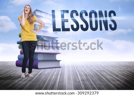 The word lessons and beautiful blonde woman laughing on the phone against stack of books against sky