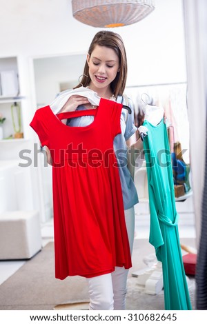 Woman deciding between two dresses in fashion boutique