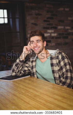 Smiling hipster phoning with smartphone at coffee shop