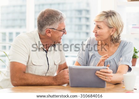 Smiling business team discussing over a tablet at office