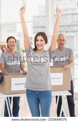 Portrait of cheering female volunteer in front of colleagues in the office