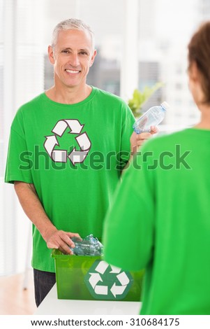Portrait of smiling eco-minded man holding recycling bottle in the office