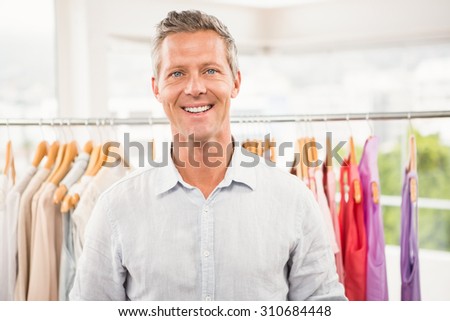 Portrait of smiling man in front of clothing rail in clothing store