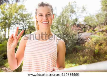Portrait of pretty blonde showing peace sign and taking selfies in the nature