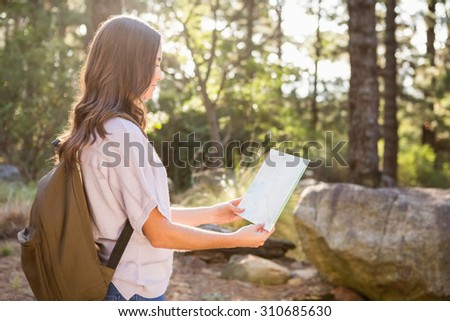 Pretty brunette hiker reading map in the nature