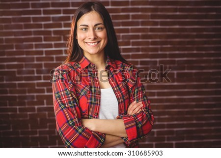 Beautiful hipster smiling at camera on red brick background