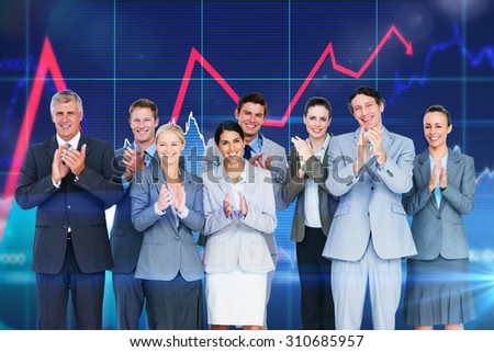 Smiling business team applauding at camera against stocks and shares