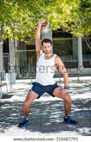 Squatting athlete outfit with a kettlebell on a sunny day