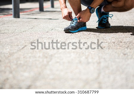 Low angle view of an athletic man tying his shoe laces