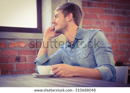 Handsome man phoning and looking out of window at coffee shop
