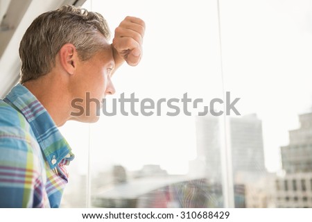 Troubled casual businessman leaning against window in the office