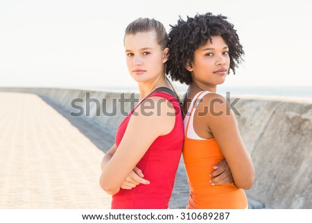 Portrait of two young women standing back to back at promenade