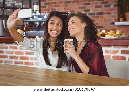 Happy women friends taking a selfie in a cafe