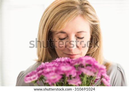 Casual businesswoman smelling at flowers in the office