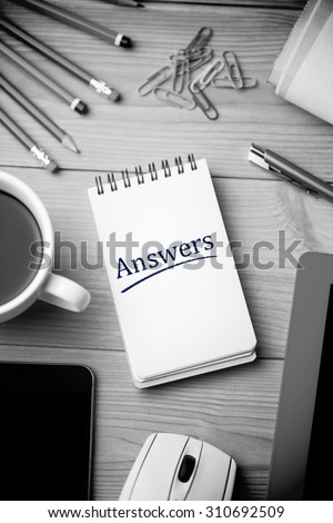 The word answers against notepad on desk