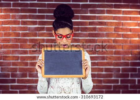 A beautiful hipster holding a blackboard against a brick wall