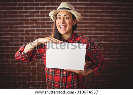 Beautiful hipster showing white card on red brick background