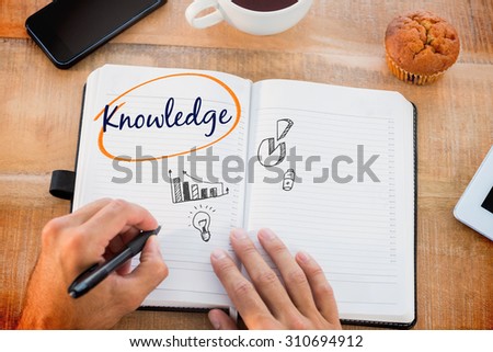 The word knowledge and man writing notes on diary against business graphs