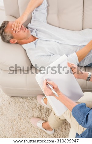 Depressed man lying on couch and talking to therapist in the office