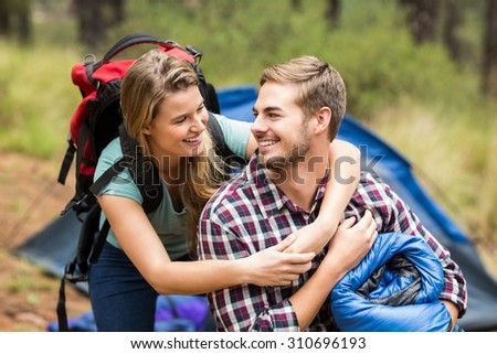 Young pretty hiker couple holding a sleeping bag and backpack in the nature
