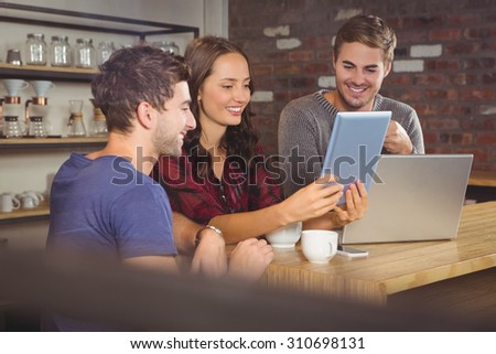 Smiling friends looking at tablet computer at coffee shop