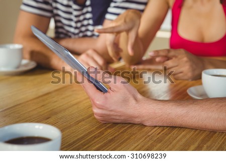 Happy friends laughing while looking at tablet at coffee shop