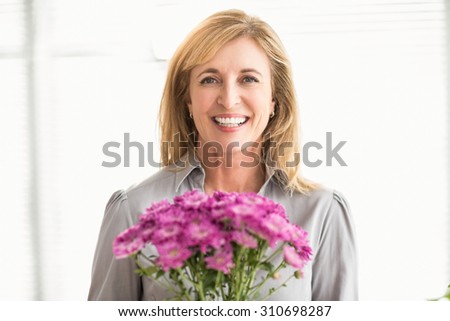 Portrait of smiling casual businesswoman holding flowers in the office