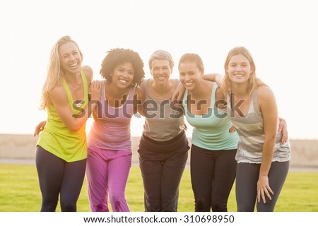 Portrait of smiling sporty women with arms around each other in parkland