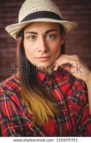 Beautiful hipster looking at camera on red brick background