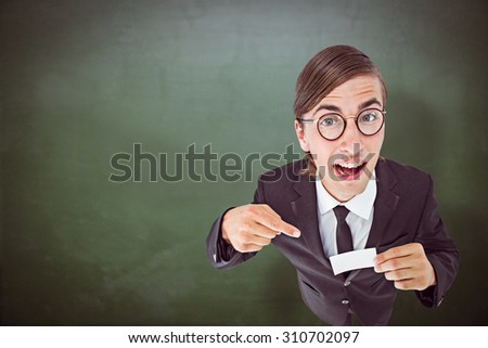 Geeky businessman looking at camera and pointing at card against green chalkboard