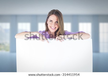 Portrait of smiling businesswoman pointing at blank billboard against room overlooking ocean