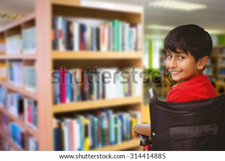 Boy sitting in wheelchair in school against volumes of books on bookshelf in library Volumes of books on bookshelf in library at the university