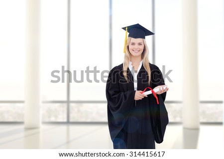 Smiling blonde student in graduate robe holding her diploma against window overlooking city