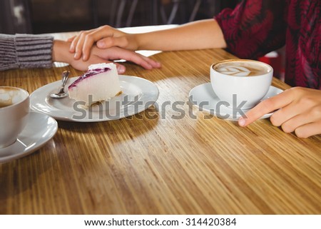 Couple holding hands and having coffee and cake together at coffee shop