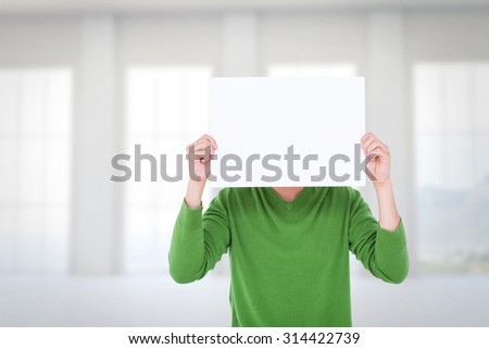 Man holding blank sign in front of face against room overlooking ocean