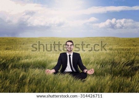 Peaceful businessman sitting in lotus pose relaxing against nature scene