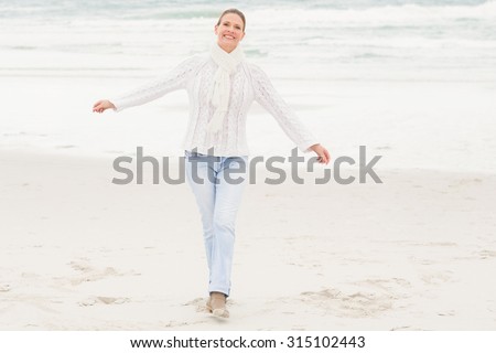 Woman standing with arms open wide at the beach