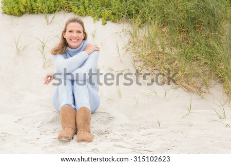 Smiling woman sitting on the sand at the beach